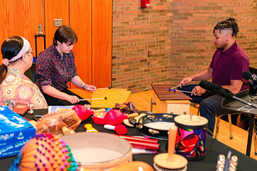 Profesionales y pacientes en sesión de musicoterapia utilizando xilófonos y maracas en ambiente colaborativo